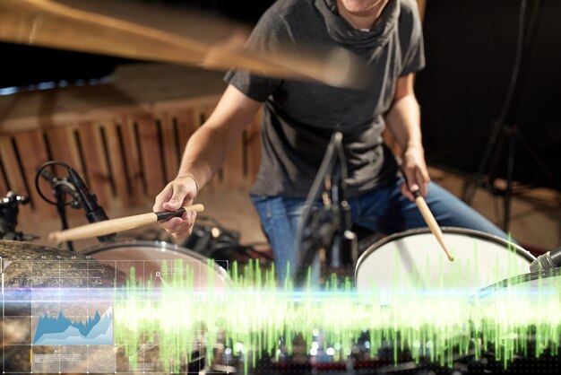 Foto musikleute musikinstrumente und technologie konzept nahaufnahme eines musikers mit trommelsticks, der bei einem konzert in einem tonaufnahmestudio ein trommelset spielt