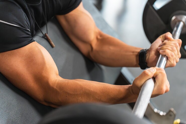 Foto muskulöse arme eines mannes, der im fitnessstudio mit der stange biceps trainiert