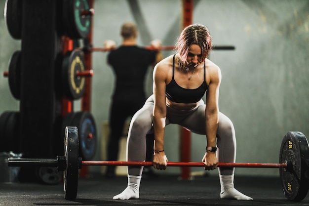 Muskulöse Frau beim Rückentraining mit Langhantel im Fitnessstudio Fitte Frau beim Gewichtheben im Fitnessstudio
