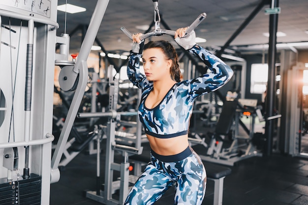 Muskulöse junge Frau, die Übungen auf dem Simulator in der Turnhalle macht. Fitness, Workout Bodybuilding Gesundheitskonzept.