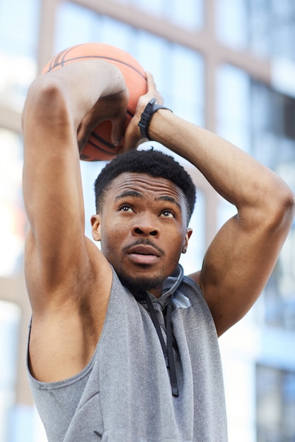 Muskulöser afroamerikanischer Mann, der Basketballball wirft