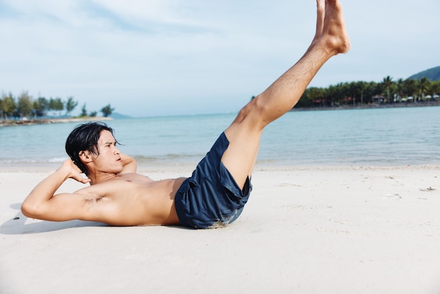 Muskulöser asiatischer Athlet, der bei Sonnenuntergang am Strand rennt und Kraft und Freiheit ausstrahlt