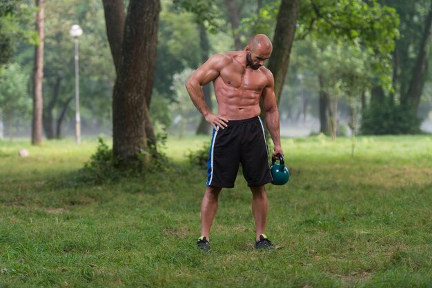 Muskulöser erwachsener kaukasischer Mann, der draußen eine Übung mit Kettlebell tut