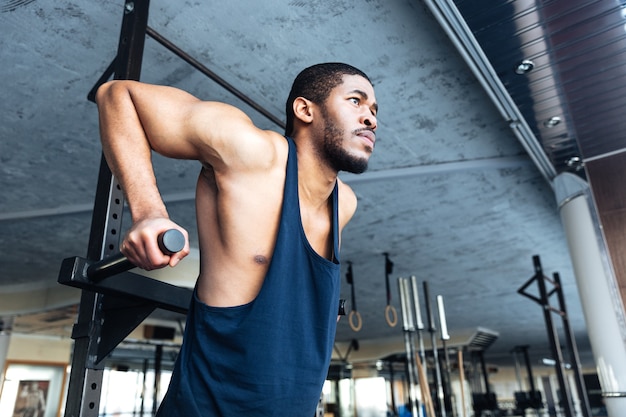 Muskulöser fitter mann macht klimmzüge im fitnessstudio mit sportgeräten