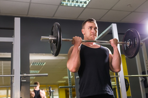 Muskulöser junger Mann, der Gewichte im Fitnessstudio hebt.