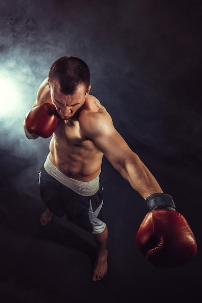 Muskulöser Kickbox oder Muay-siamesischer Kämpfer, die im Rauche lochen