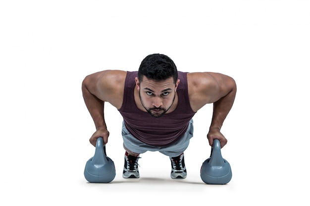 Muskulöser Mann, den das Handeln drückt, ups mit kettlebells