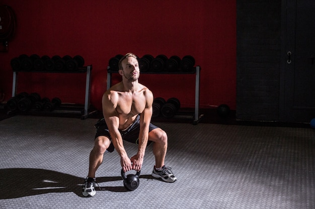 Muskulöser Mann, der ein kettlebell anhebt