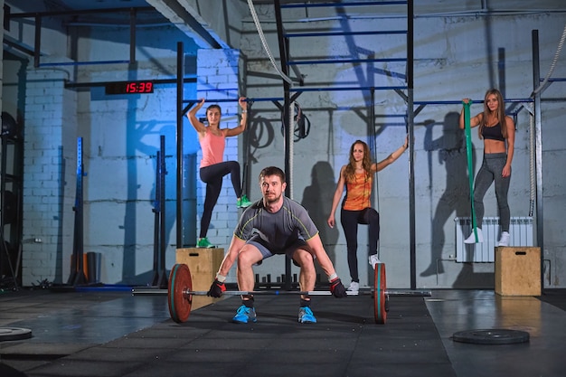 Muskulöser Mann, der Hocken mit Barbell in einer Turnhalle tut