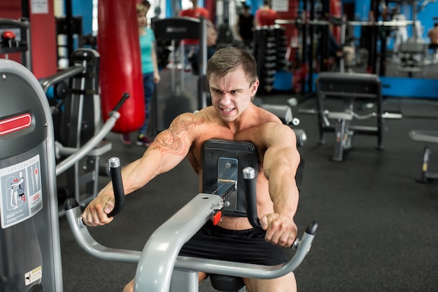 Muskulöser mann, der im fitnessstudio übungen macht, starker mann