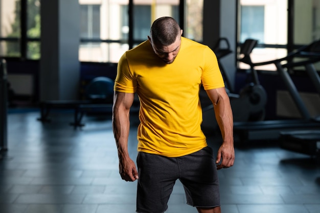 Muskulöser mann, der im gelben t-shirt aufwirft