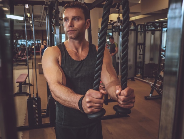 Muskulöser Mann, der in einem Fitnessstudio Trizeps trainiert.