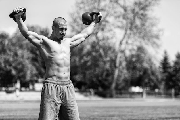 Muskulöser Mann, der mit Kettlebell im Freien trainiert