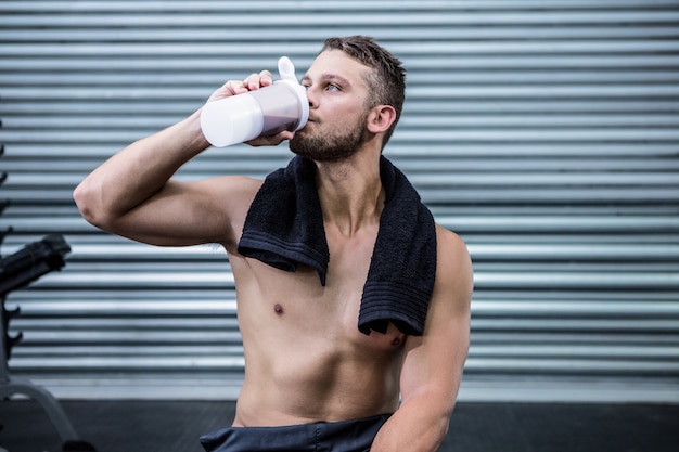 Muskulöser Mann, der Proteincocktail trinkt