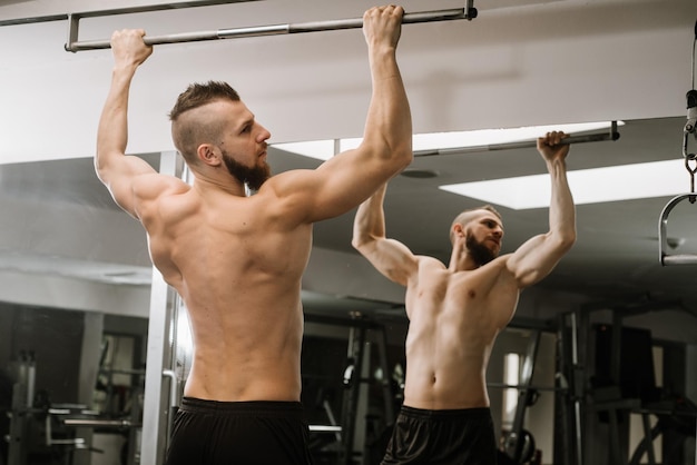 Muskulöser Mann hebt seinen Körper im Fitnessstudio