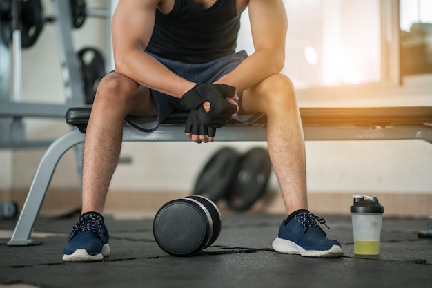 Muskulöser Mann im Fitnessstudio macht eine Pause vom Training auf der Seite MineralsalzKörper und Geist trainieren im Loft-Fitnessstudio