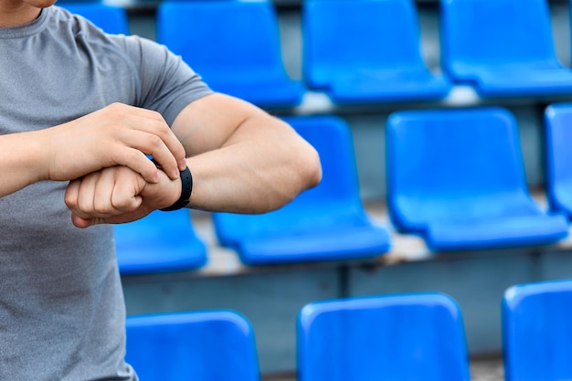 Muskulöser Mann im grauen T-Shirt schaut auf die Zeit, die auf den Start des Spiels im Stadion wartet