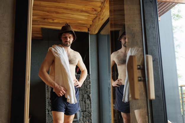 Muskulöser Mann in der Sauna mit einem Handtuch auf den Schultern