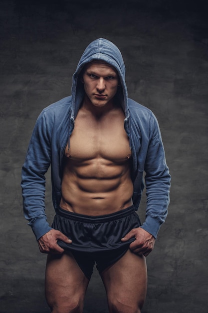 Muskulöser Mann in einem blauen Hoodie, der seine athletischen Beine zeigt.
