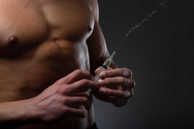 Muskulöser Mann mit einer Spritze in der Hand Benutzer von anabolen Steroiden für das Krafttraining