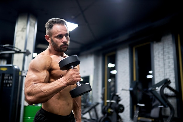 Muskulöser Mann mittleren Alters trainiert im Fitnessstudio im Innenraum Seitensicht eines starken kaukasischen Athleten, der trainiert