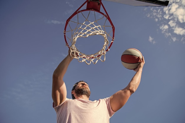 Muskulöser Mann Spieler wirft Basketballball durch Korb männlicher Basketball