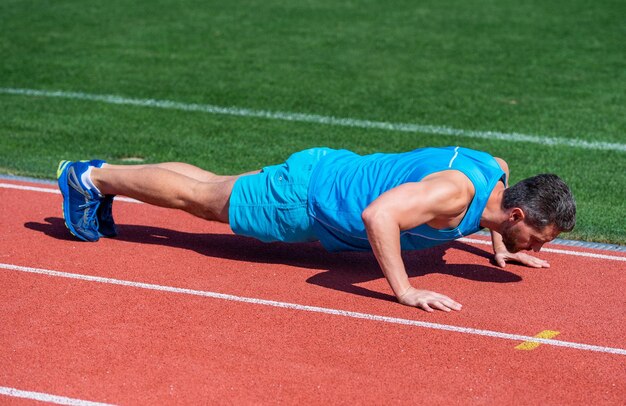 Muskulöser Mann steht in Planken und macht Sporttrainingsenergie