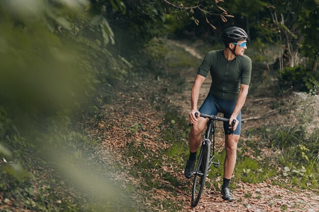 Muskulöser Mann trainiert auf dem Fahrrad im grünen Stadtpark