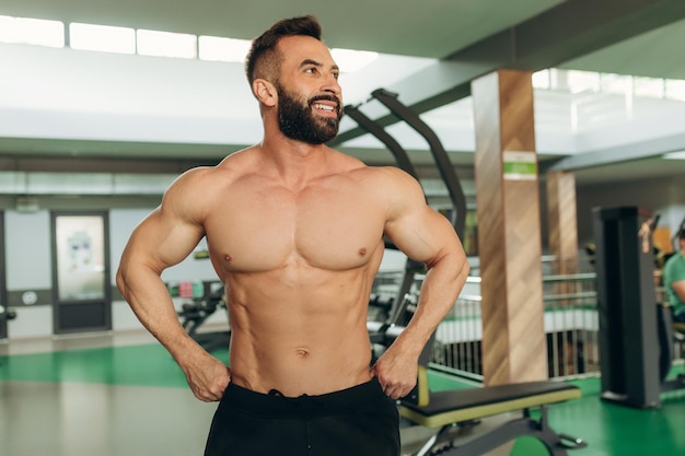Muskulöser Modellmann im Fitnessstudio Modeporträt eines starken brutalen Kerls mit trendiger Frisur Sexy nackter Torso Sixpack abs Männlich, der seine Muskeln beugt Sport-Workout-Bodybuilding-Konzept
