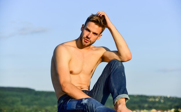 Muskulöser, nackter Oberkörper, Sommer-Lookbook, Fitness-Modell, athletischer, gutaussehender Macho in Jeanshosen, muskulöser Körper, Sixpacks, muskulöse Brust, Mann im Freien, blauer Himmelshintergrund, männliches Schönheitskonzept