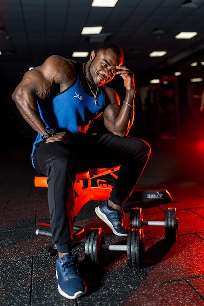 Muskulöser Typ mit nacktem Oberkörper, der mit der Hand in der Nähe des Kopfes posiert Fitnessstudio-Hintergrund Porträt eines gutaussehenden afroamerikanischen Mannes