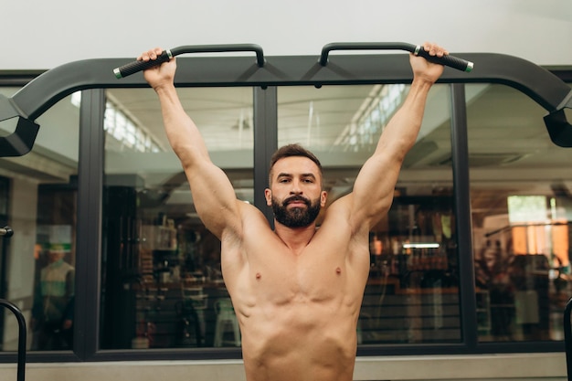 Muskulöser Typ trainiert an der horizontalen Stange im Fitnessstudio