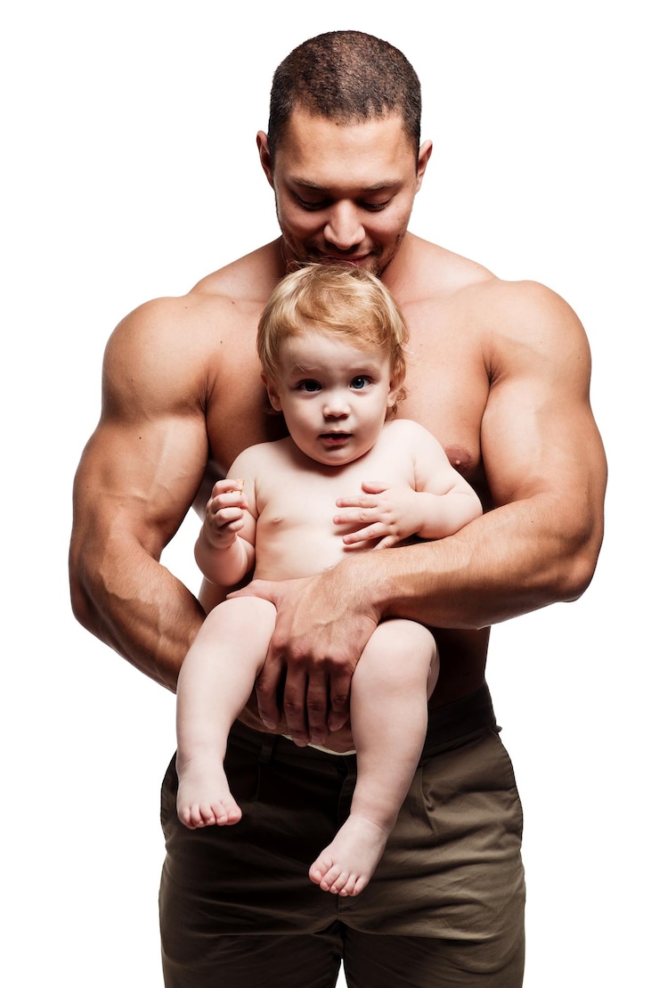 Foto muskulöser vater hält eine niedliche tochter in der hand, während er vor weißem hintergrund steht