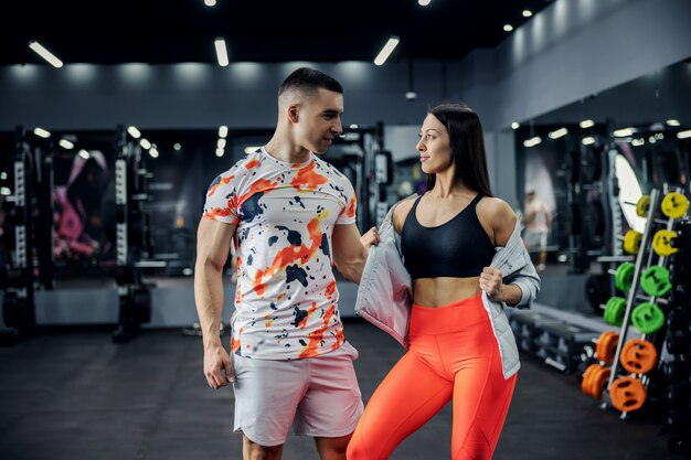 Muskulöses Paar, das im Fitnessstudio steht und aufwirft. Indoor Fitness, Beziehung, gesundes Leben