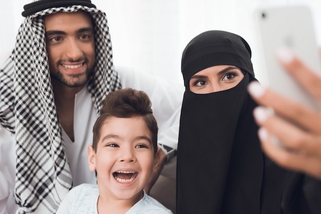 Muslime sitzen zu Hause und machen ein Selfie am Telefon.