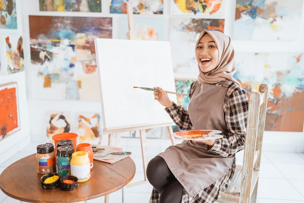 Muslimische asiatische Künstlerin malt auf Leinwand