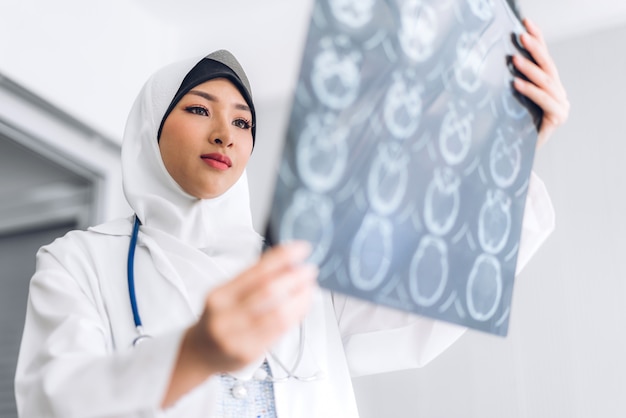 Muslimische asiatische Ärztin, die Röntgenfoto betrachtet