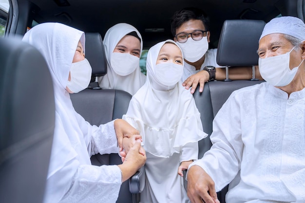 Muslimische Familie mit Gesichtsmaske sitzt im fahrenden Auto