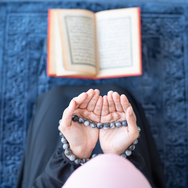 Muslimische Frau beten mit Perlen und lesen Koran