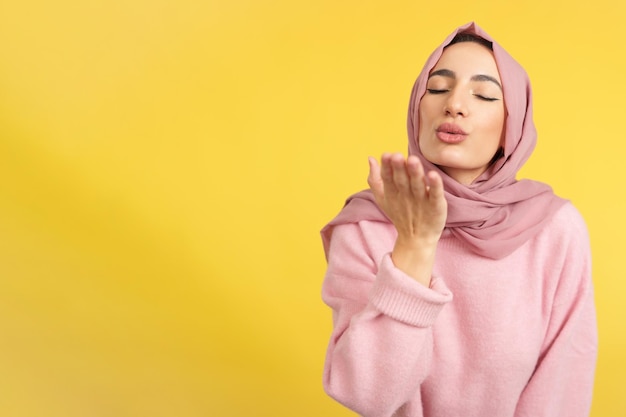 Muslimische Frau bläst einen Kuss mit geschlossenen Augen