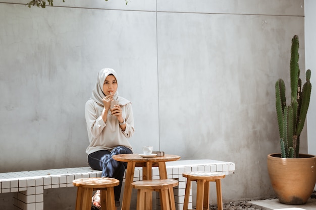 Muslimische Frau, die Eiskaffee genießt