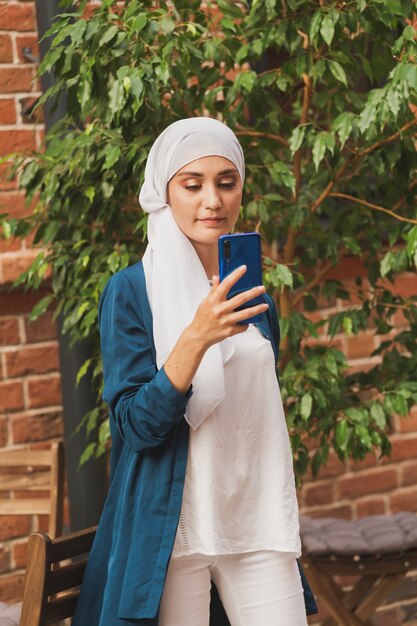 Muslimische Frau, die selfie macht, glückliches schönes Mädchen mit Schal, fotografieren Sie sich selbst mit dem Smartphone