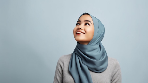 Muslimische Frau in blauem Pullover und Hijab denkt über eine Idee nach, während sie nach oben schaut
