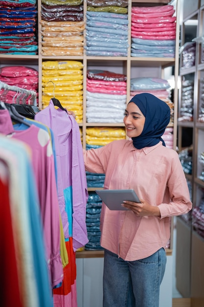 Muslimische Frau in ihrem Modelager, die das Produkt überprüft