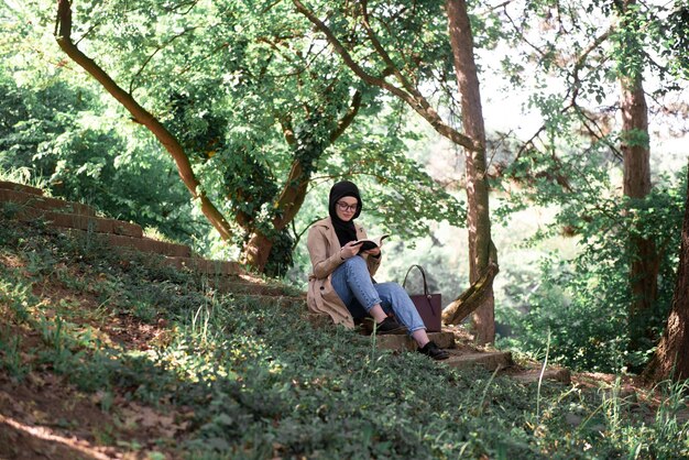 Muslimische Frau liest ein Buch im Park während ihrer Freizeit