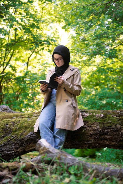 Muslimische Frau liest ein Buch im Park während ihrer Freizeit