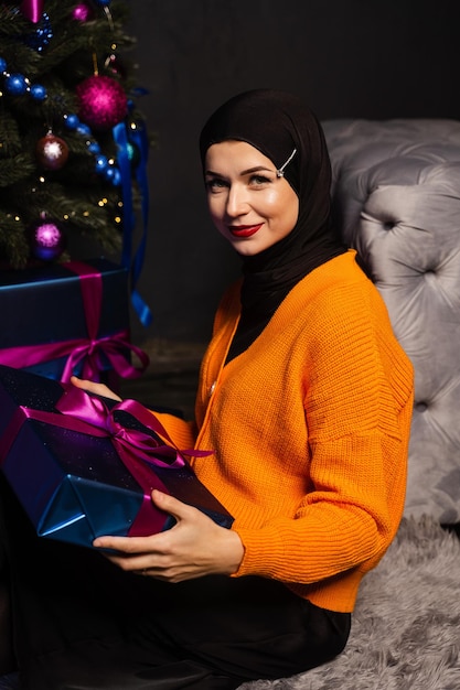 Muslimische Frau mit Geschenk nahe Baum des neuen Jahres Weihnachtsfeier der Menschen der Islamreligion.