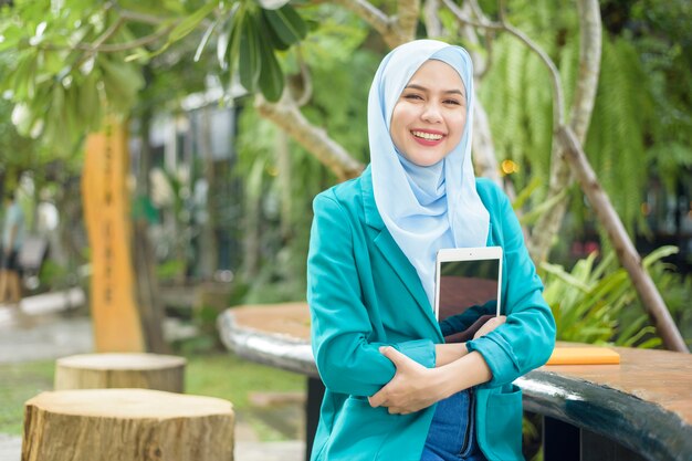 Muslimische Frau mit Hijab arbeitet mit Tablette in einem Café