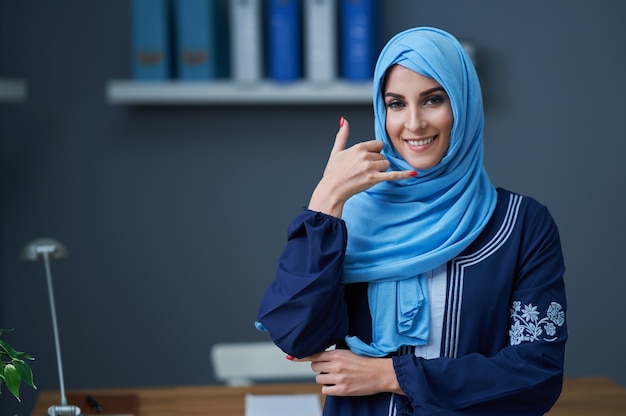 Muslimische Frau mit Smartphone im Büro