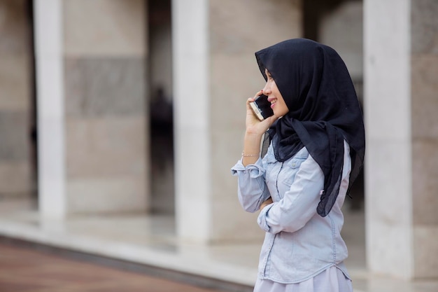 Muslimische Frau mit Smartphone in Moschee